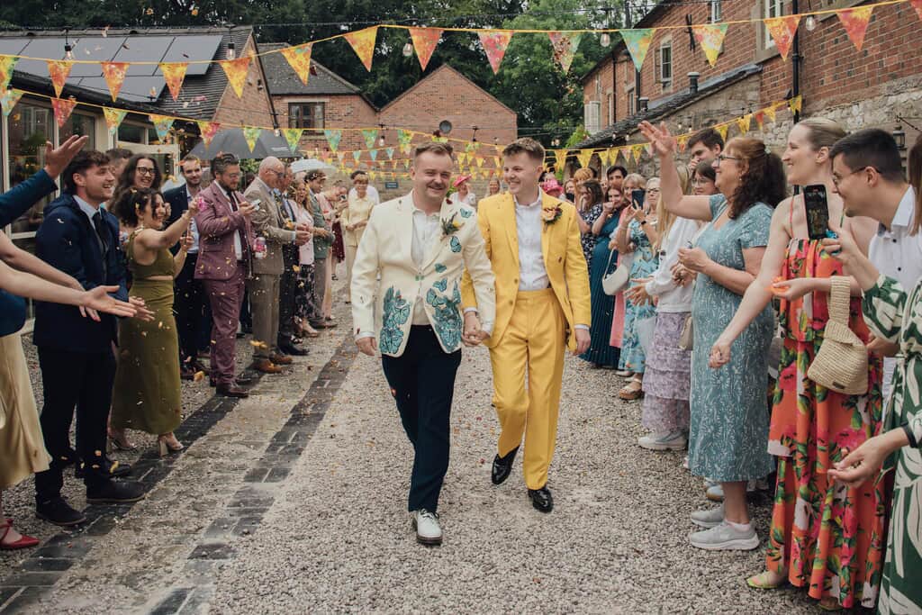 Image showing the happy couple of Tom & Will walking the street of Knockerdown Cottages during their wedding.